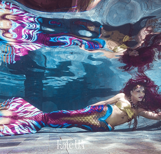 Aquatic mermaid model swimming underwater in a colorful patterned tail