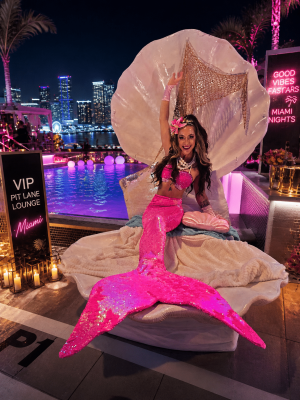 All-pink glamour mermaid in a clamshell throne at a Miami Beach party